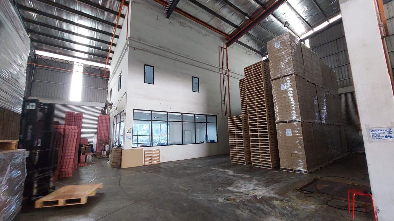 The Johor Bahru floor, cartons stacked several levels high against the far wall beside empty pallets.