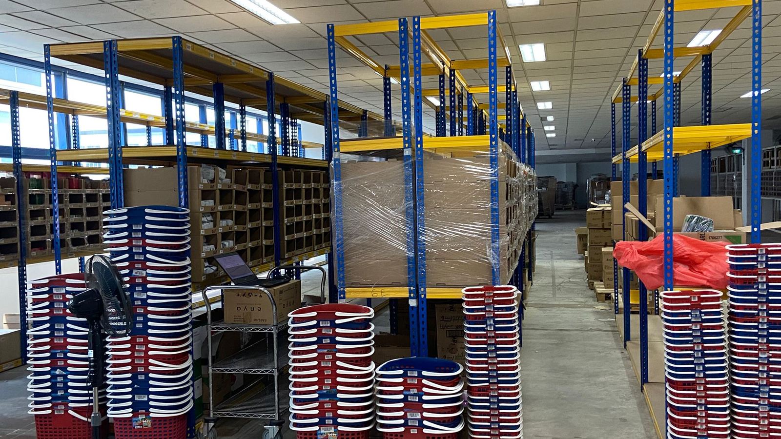 A racked aisle in the Singapore centre, bin shelving to full height with stacked stock in the foreground.