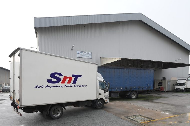 An SnT box truck drawn up under the canopy at a loading dock.